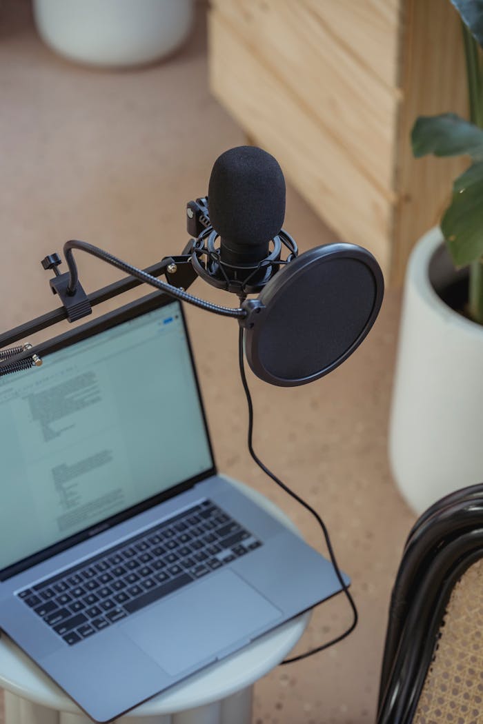 A modern podcast setup featuring a laptop and studio microphone on a desk, ideal for digital media production.